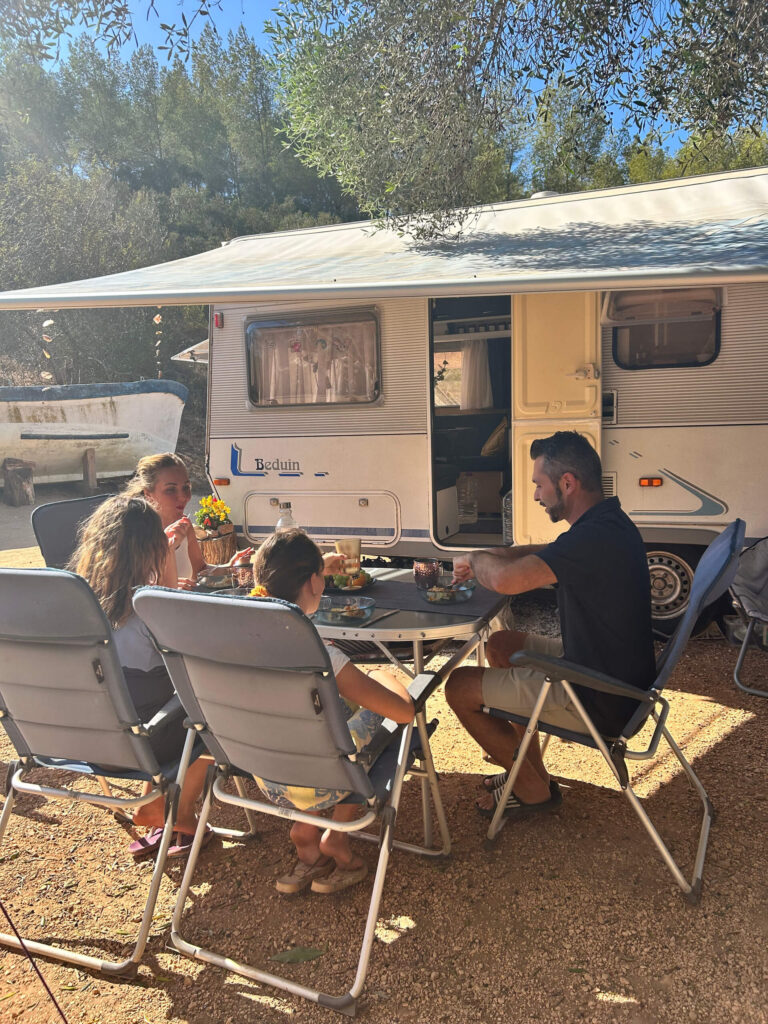 Família a fazer a sua refeição no espaço exterior da sua carrinha.