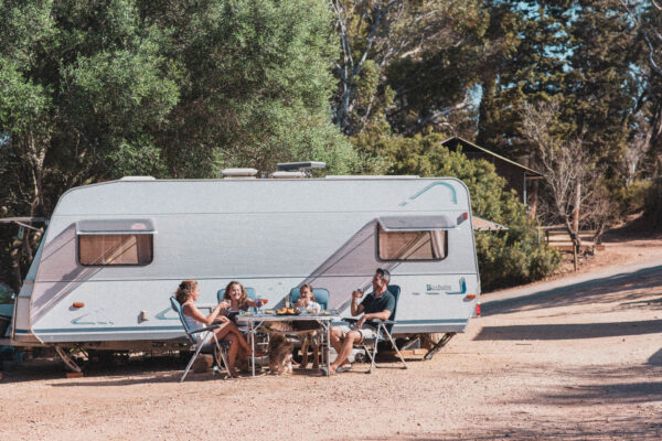 Pessoas sentadas conversando em frente a um mobile home
